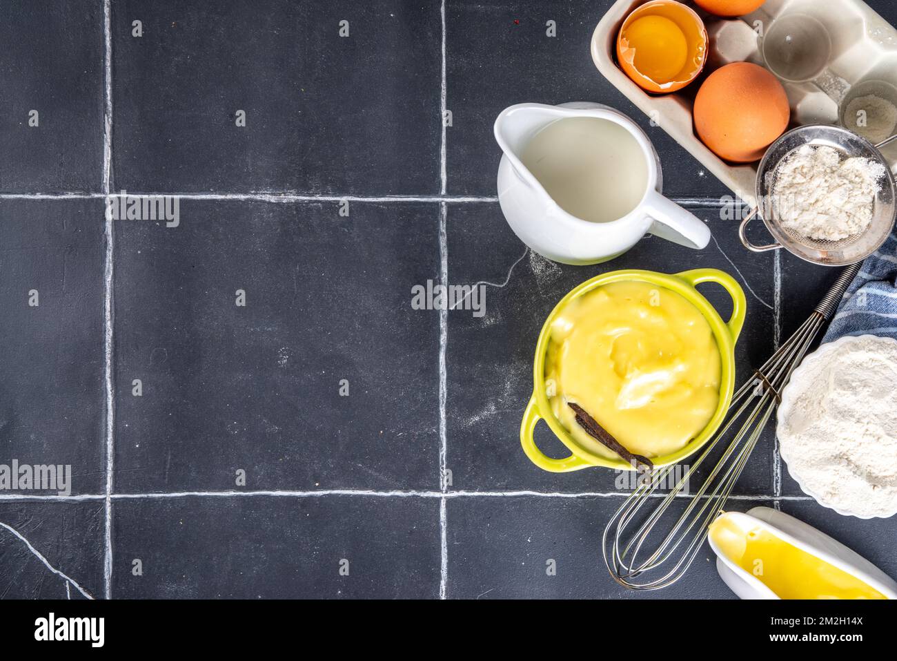 Homemade custard creme with ingredients - vanilla, milk and eggs. Sweet Creme anglaise dessert cooking background, on black kitchen table copy space Stock Photo