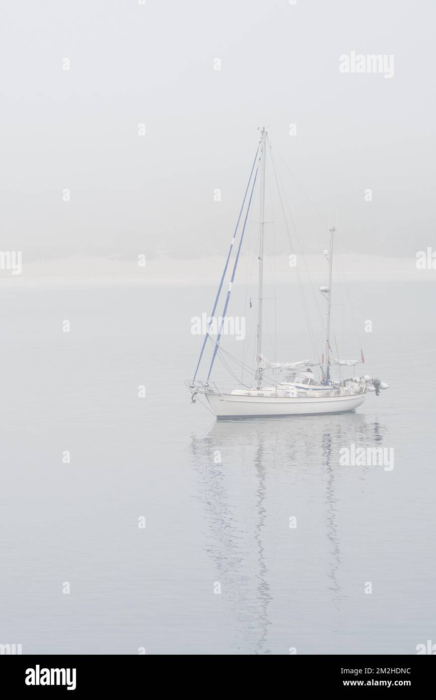 Sailboat / sailing boat / yacht with lowered sails anchored near beach