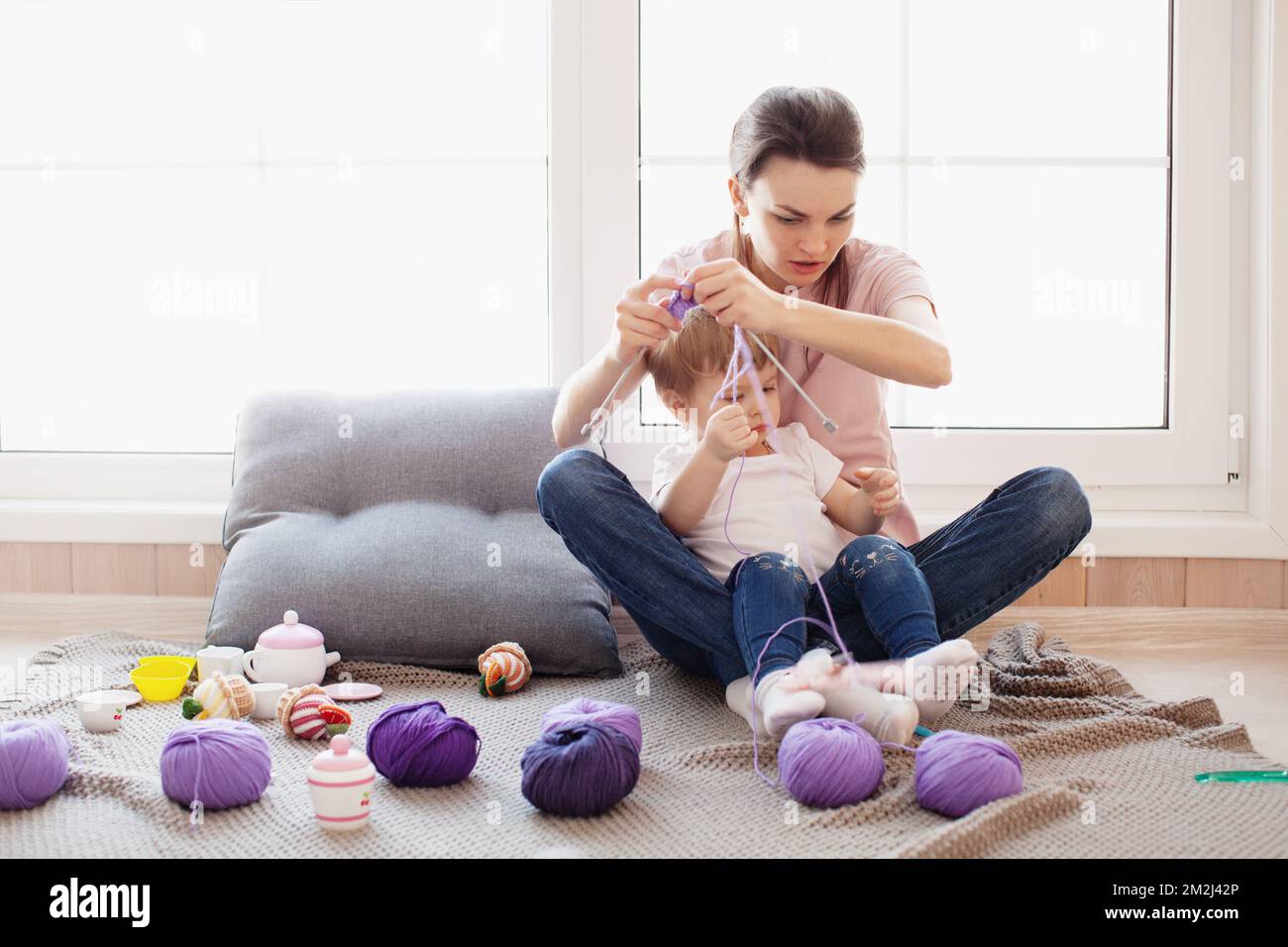 Child daughter prevent woman mother work knit at home . Lifestyle