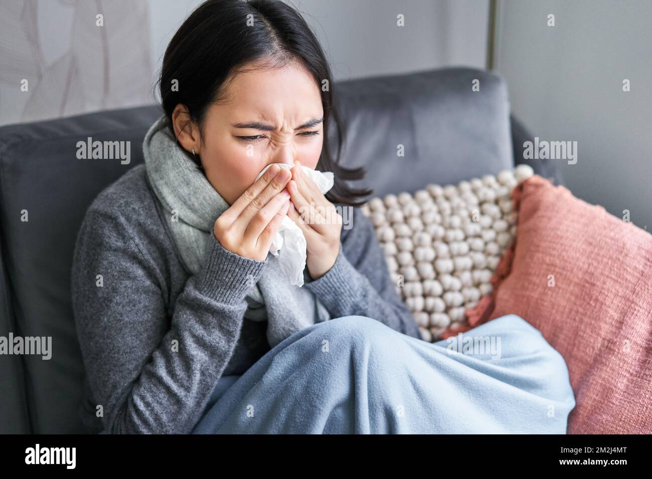 Image of sick korean woman at home, covered in warm clothes and scarf