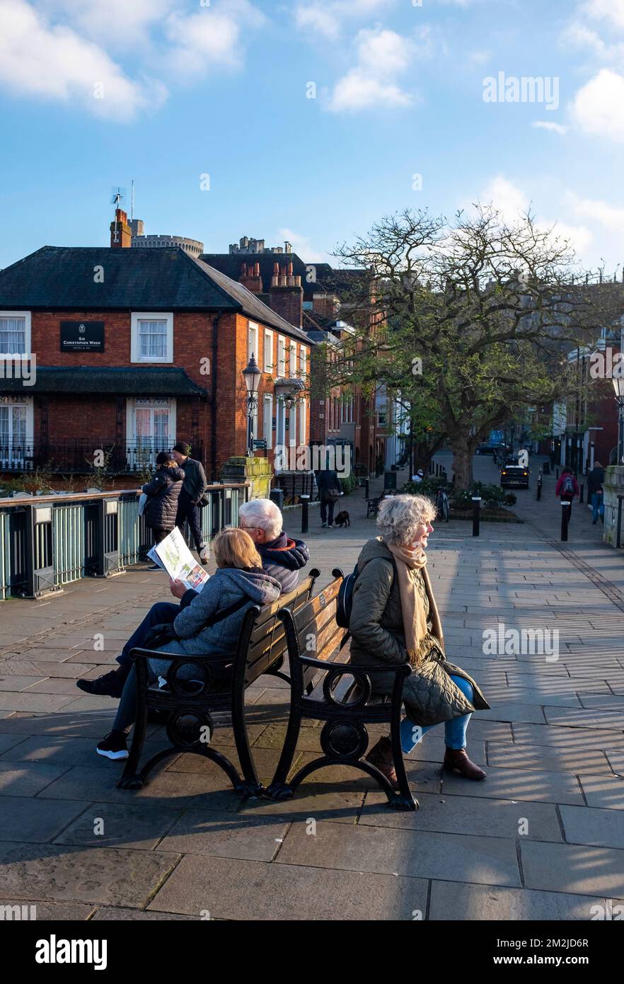 People sitting on a bench on a bridge which connects Windsor and Eton in Berkshire , England , UK Stock Photo