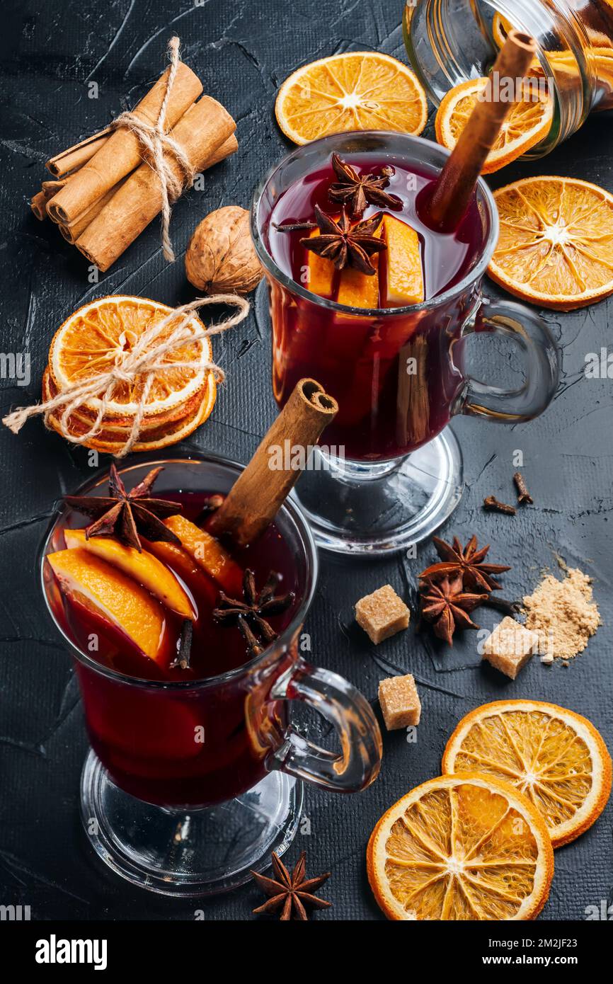Two cup of mulled wine on the table, near it are cinnamon, citrus