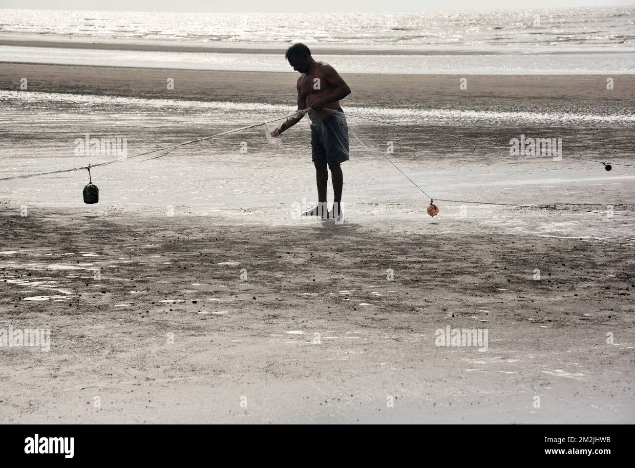 Fisherman repairing fishing net, Bhagal beach, Valsad, Gujarat, India, Asia Stock Photo