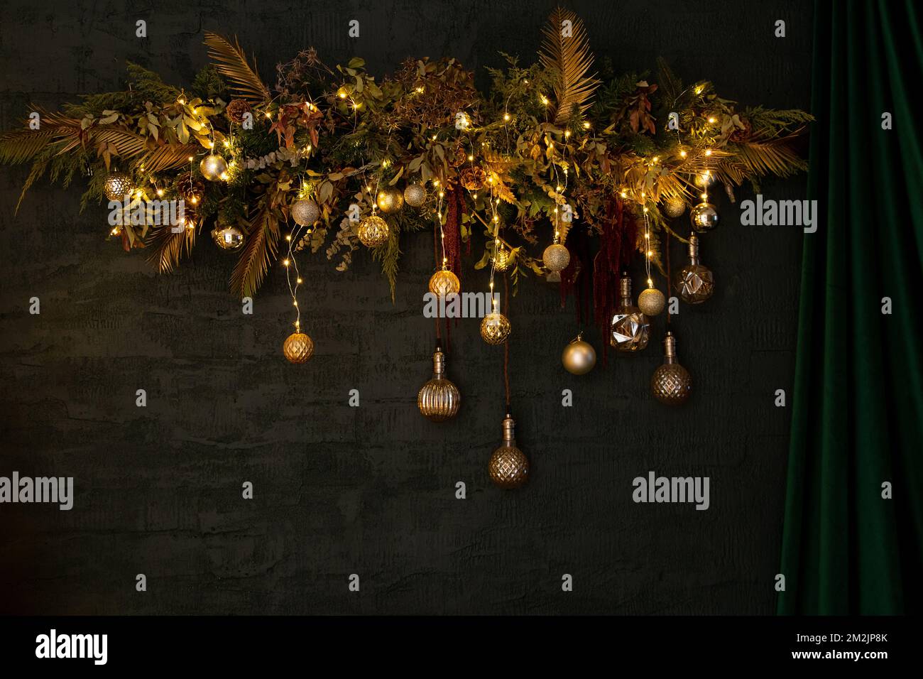 A Christmas tree wreath with garlands and toys hangs on a green wall ...
