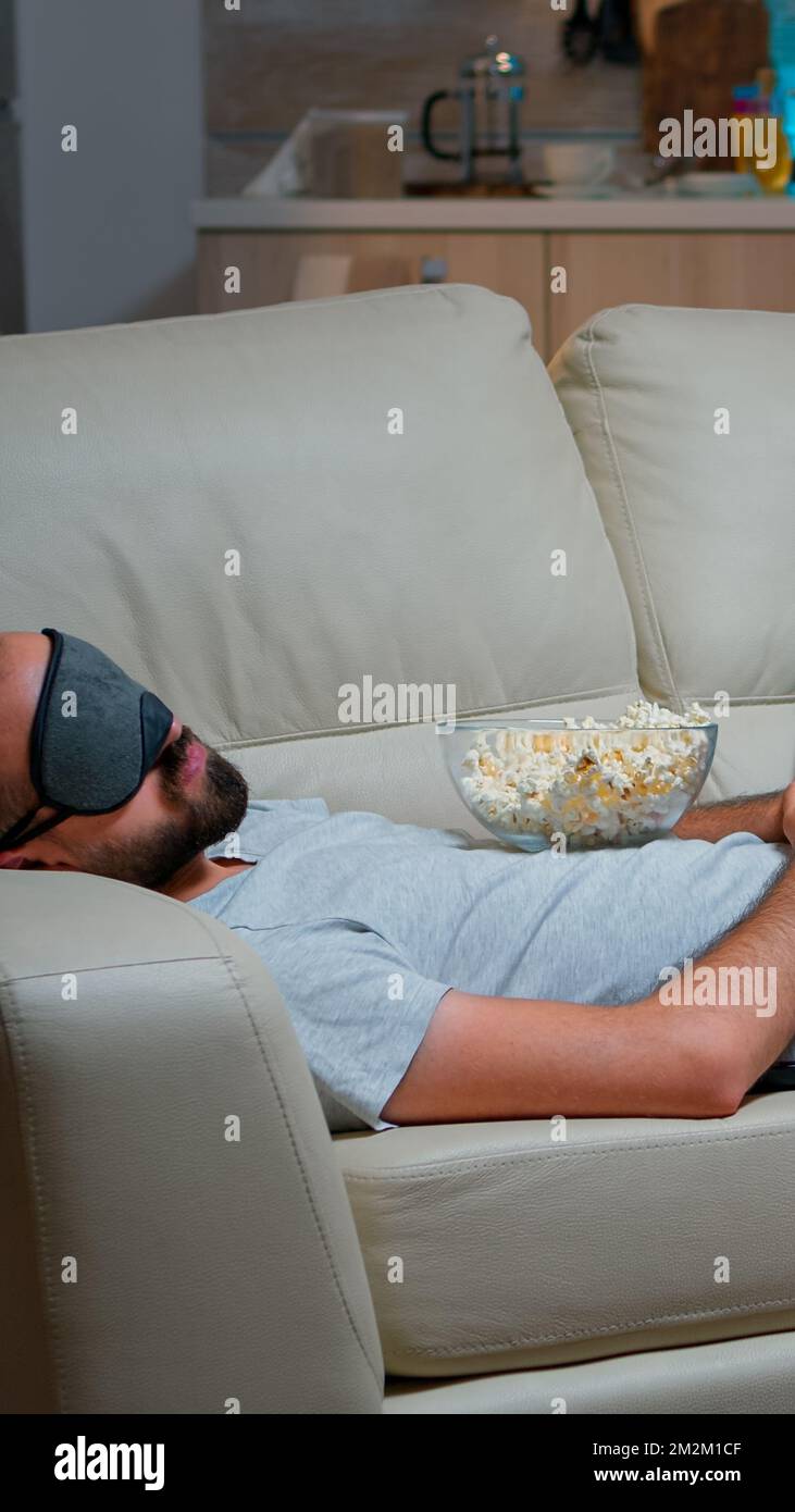 Man eye sleep mask falling asleep while watching movie, sitting in