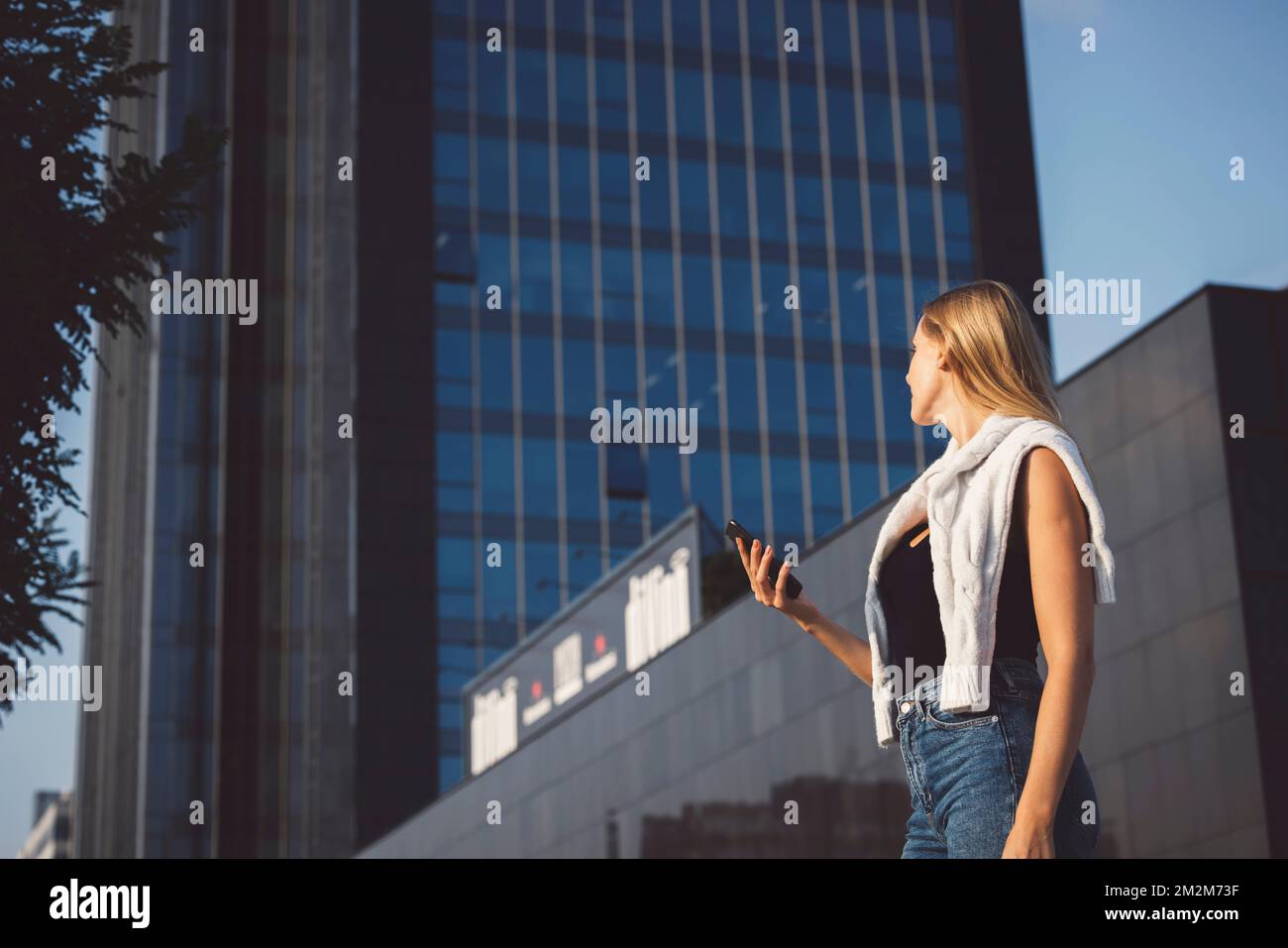 Young blonde woman in an urban setting using a mobile device Stock Photo