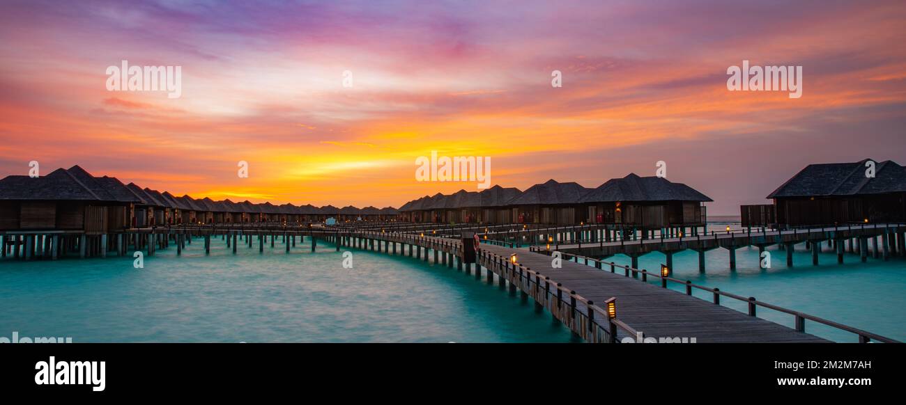 Night time long exposure landscape, over water villas in Maldives. Amazing sunset panorama at Maldives. Luxury resort villas seascape with soft lights Stock Photo