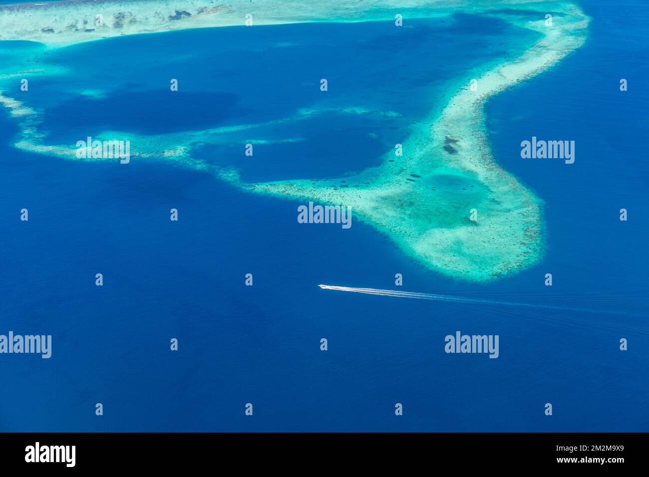 Aerial view of Maldives atolls islands with a speedboat, world top beauty. Maldives tourism, luxury travel destination aerial landscape, seascape Stock Photo