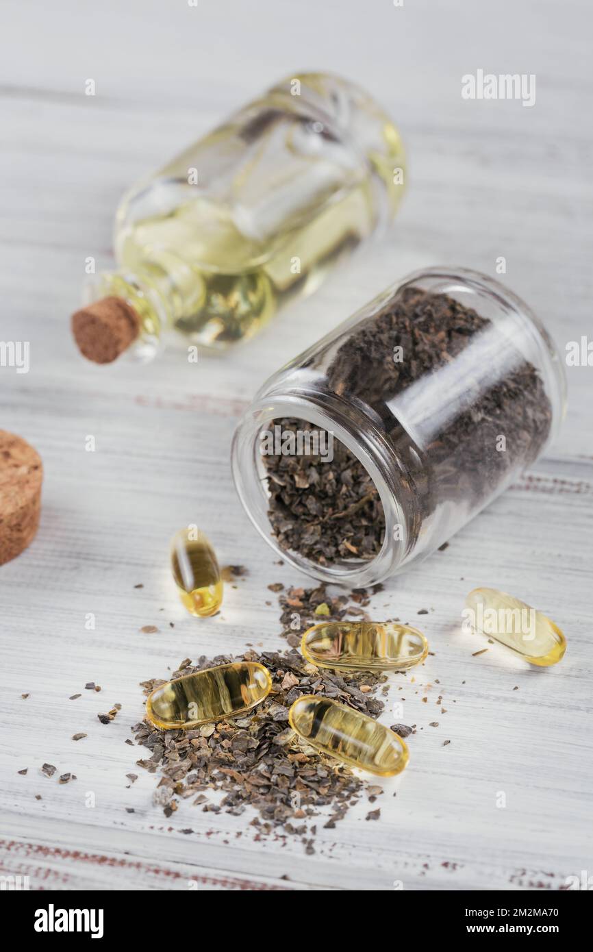 Gelatin capsules with algae omega oil and seaweed on a white wooden