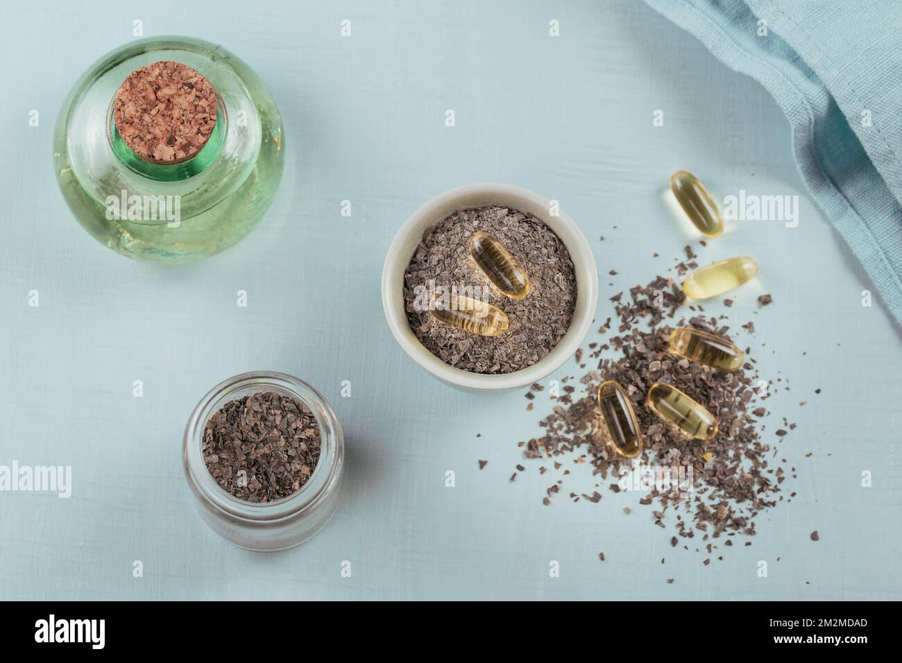 Gelatin capsules with algae omega oil and seaweed on a light blue