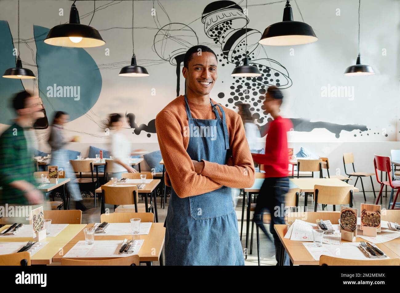 portrait of smiling male owner or waiter in cafe with unrecognizable ...