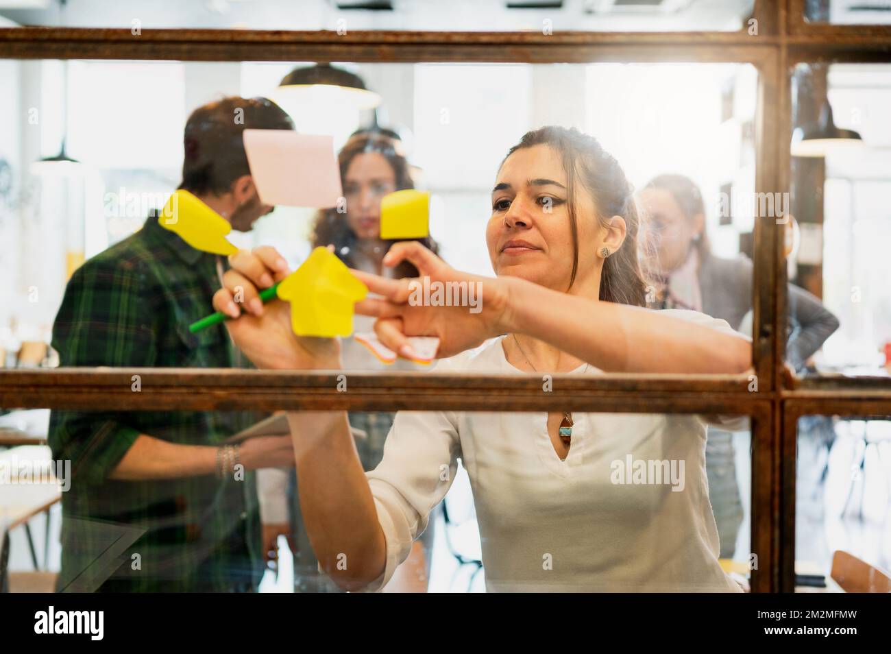 Photo through the glass of attractive businesswoman putting post ...
