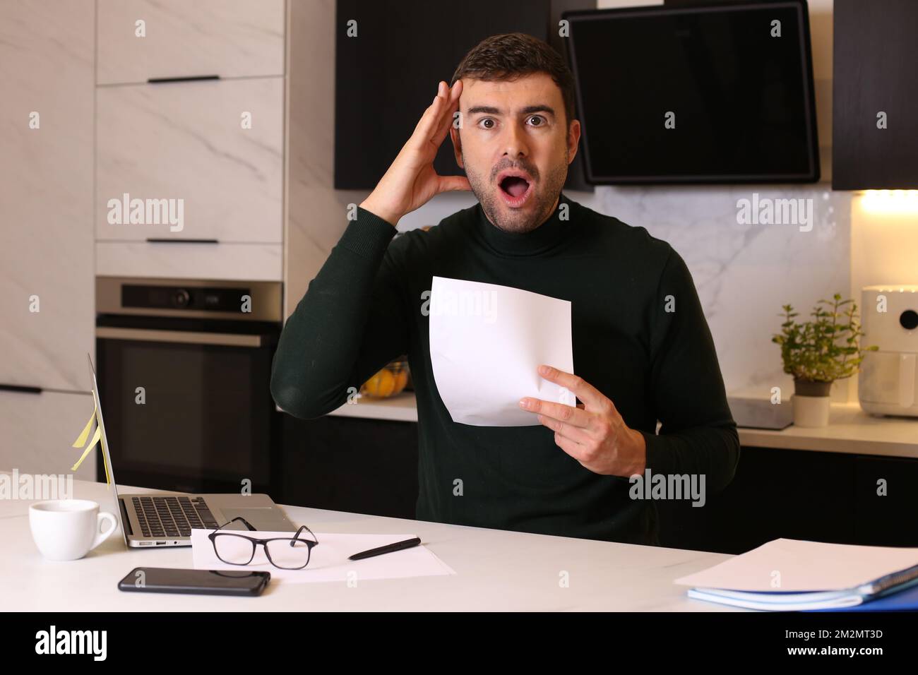 Worried looking man holding document while working from home office Stock Photo