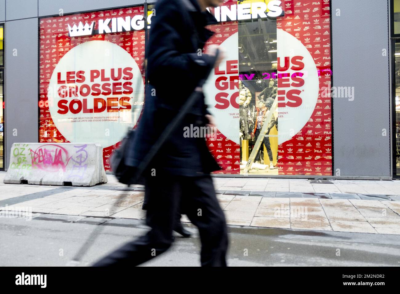 A man passes a shop with large sales stickers at the official