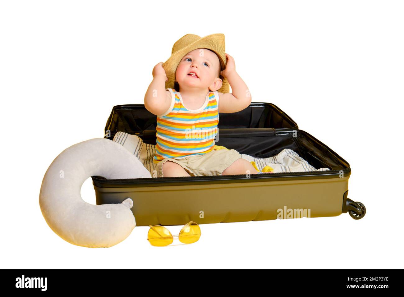 Baby toddler boy sits inside a suitcase with clothes, studio isolated