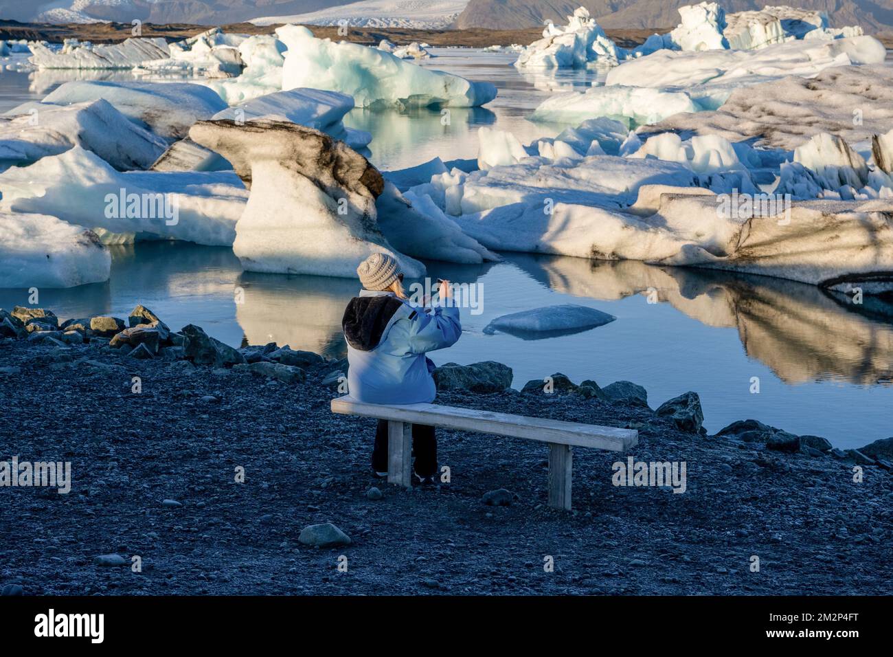 October 18, 2022, JÃ¶kulsÃrlÃ³n, JÃ¶kulsÃrlÃ³n, Iceland: A person is seen taking pictures near the shore of Lake JÃ¶kulsÃrlÃ³n. JÃ¶kulsÃrlÃ³n is a lake located in southern Iceland, with an area of 20 km2 and a depth of over 200 meters. Until less than 100 years ago, the BreiÃ°amerkurjÃ¶kull glacier (part of the VatnajÃ¶kull glacier) extended even beyond the ring road. Due to rising temperatures, the glacier has retreated, creating this impressive glacial lagoon. (Credit Image: © Jorge Castellanos/SOPA Images via ZUMA Press Wire) Stock Photo