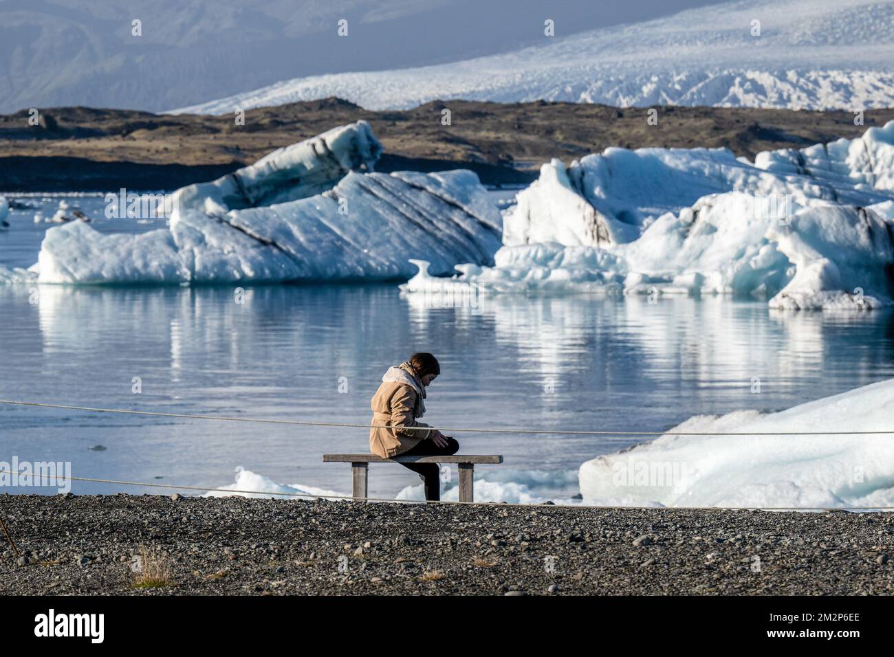 October 19, 2022, JÃ¶kulsÃrlÃ³n, JÃ¶kulsÃrlÃ³n, Iceland: A person is seen resting near the shore of Lake JÃ¶kulsÃrlÃ³n. JÃ¶kulsÃrlÃ³n is a lake located in southern Iceland, with an area of 20 km2 and a depth of over 200 meters. Until less than 100 years ago, the BreiÃ°amerkurjÃ¶kull glacier (part of the VatnajÃ¶kull glacier) extended even beyond the ring road. Due to rising temperatures, the glacier has retreated, creating this impressive glacial lagoon. (Credit Image: © Jorge Castellanos/SOPA Images via ZUMA Press Wire) Stock Photo