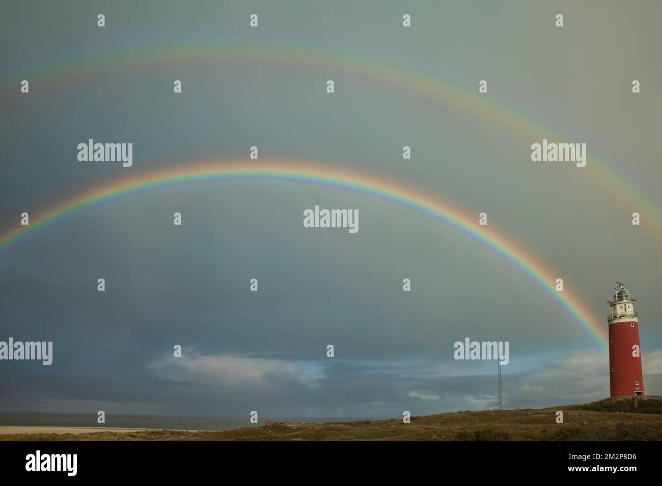 rainbow above the sea with the lighthouse of Texel on the right Stock Photo