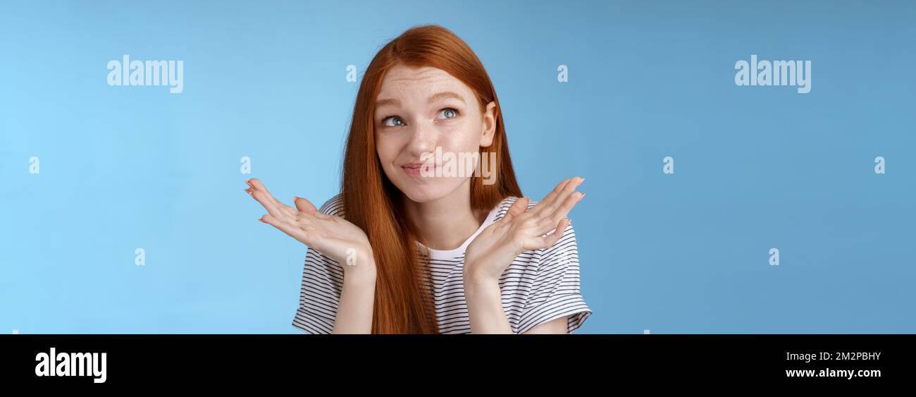 Awkward uncomfortable attractive redhead popular girl trying think up excuse feeling reluctant uncertain standing doubtful shrugging spread hands Stock Photo