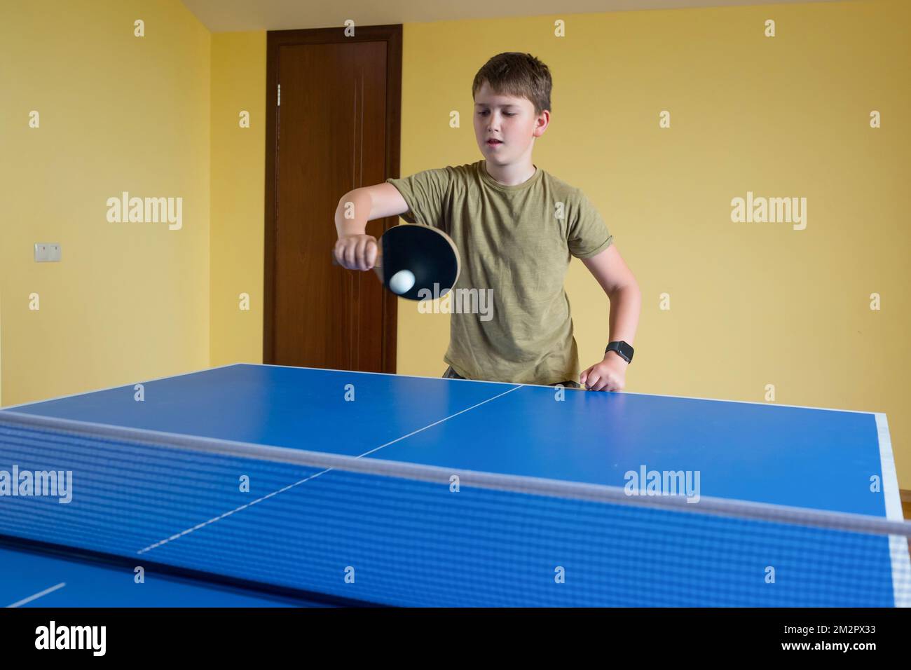 little boy wearing blue shirt playing ping pong, concentrated face