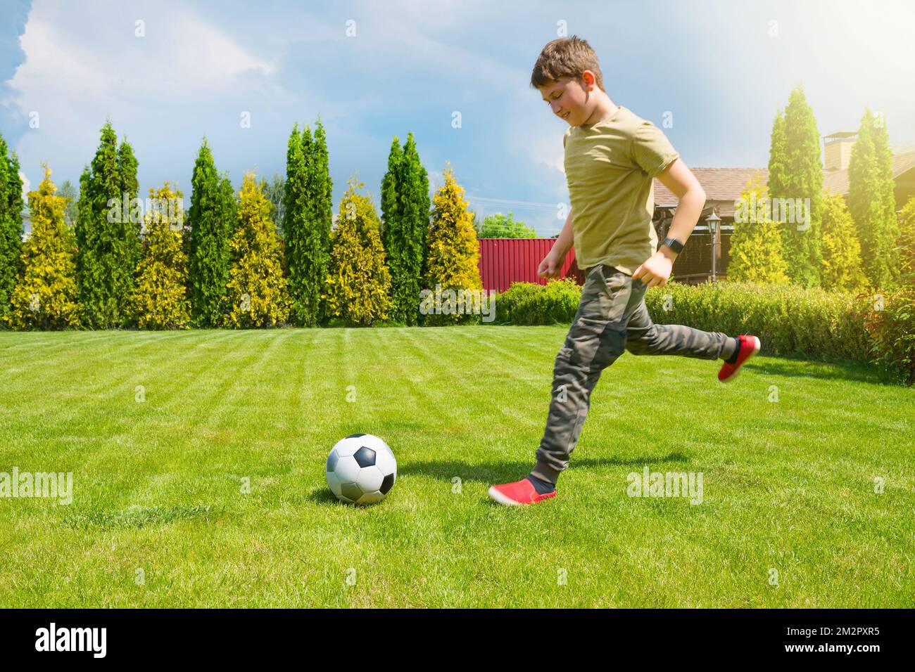 An 11-year old teenager is playing football in the house backyard. Sport lifestyle Stock Photo