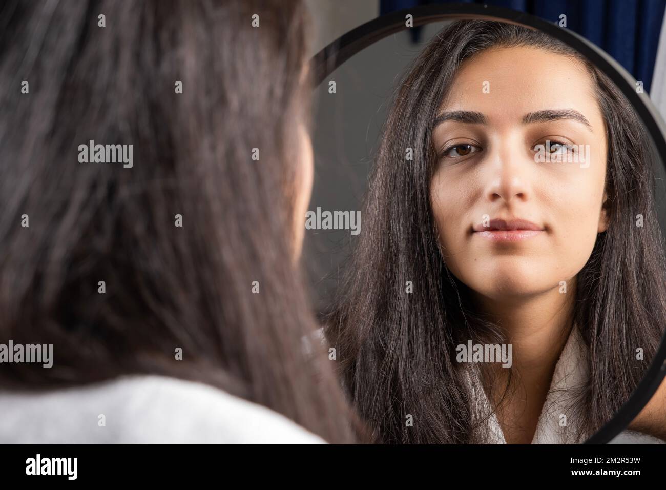 Beautiful caucasian brunette woman looking mirror. Gently smiling confident happy millennial girl.  Ready for evening she did her makeup concept idea. Stock Photo