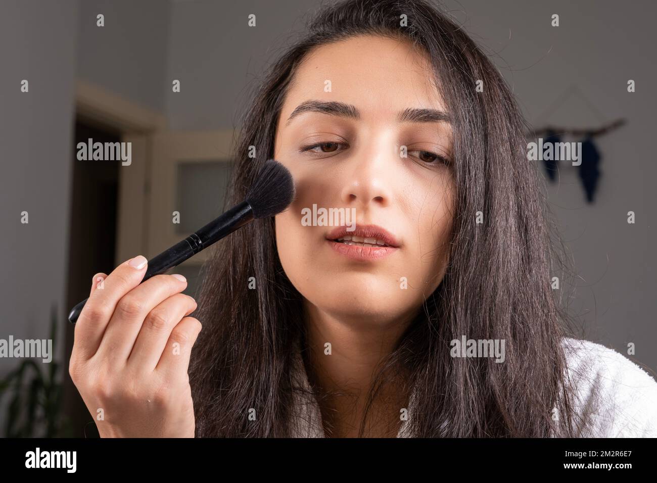 Beautiful brunette caucasian girl holding make up brush. Refreshing her make up for the night. Gently open her mouth. Enjoy her skin and beauty. Stock Photo