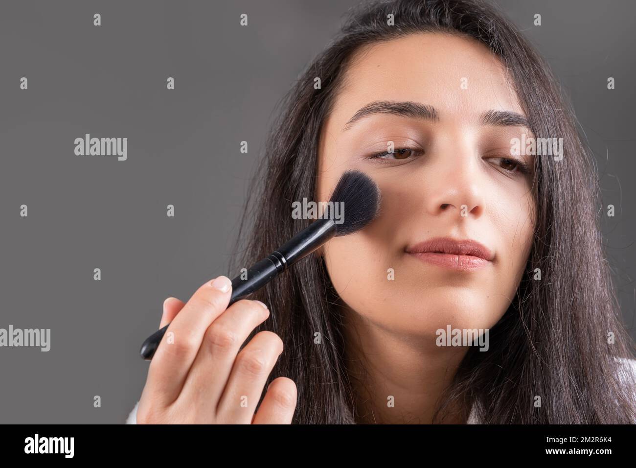 Applying blush, young caucasian girl. Face powders, using brush for