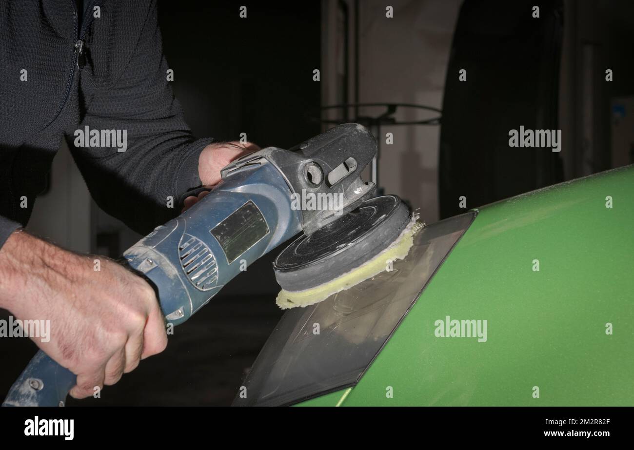 Polishing car headlights. Car service worker with electrical polisher