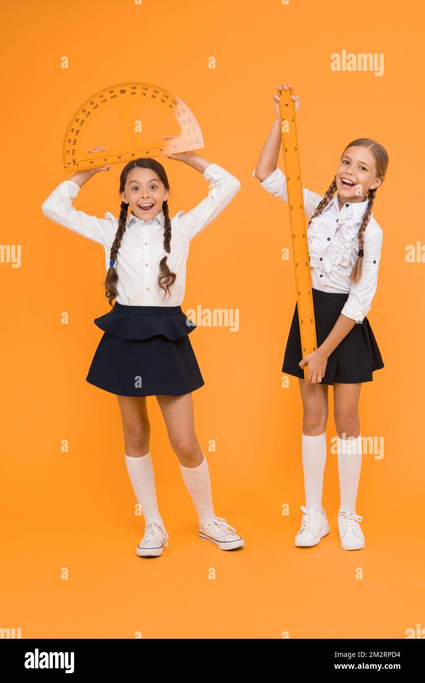 Formula. back to school. Maths and geometry. Kids in uniform at yellow wall. friendship and sisterhood. happy small girls study mathematics. students Stock Photo