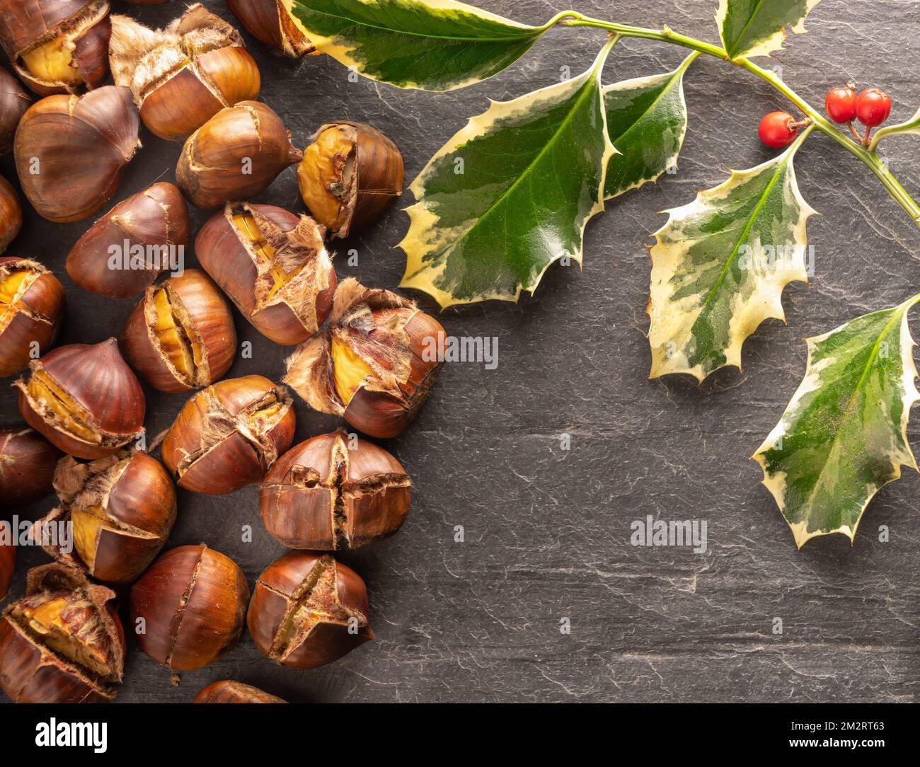 Roasted chestnuts with Christmas holly Stock Photo