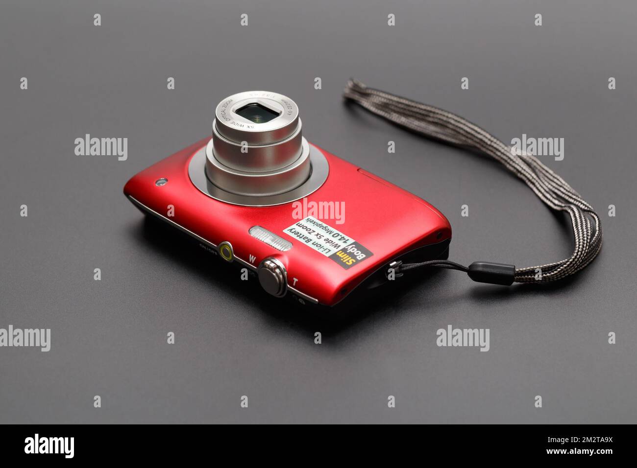 Compact red camera with a retractable lens closeup on a gray