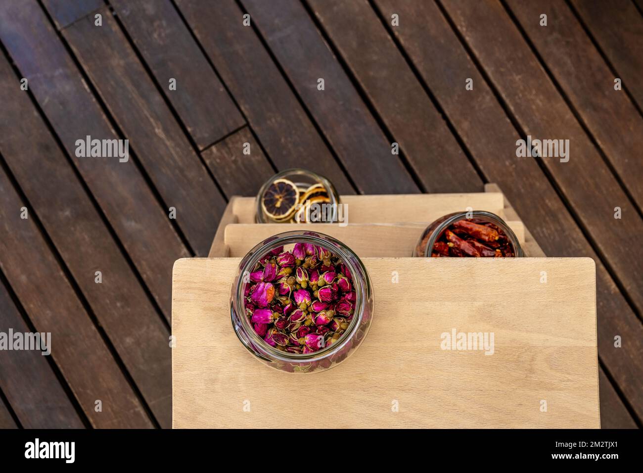Glass jars with dried flowers, chilli peppers and dehydrated orange slices on a three-step ladder with sinar varnish Stock Photo