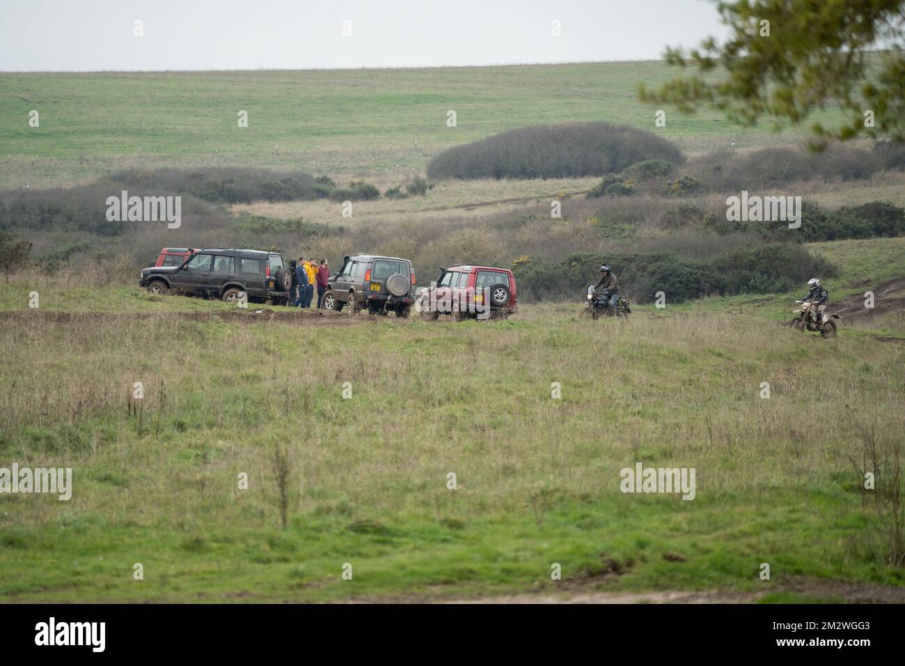 a group of land rover discovery 4x4 off-road vehicles being driven through deep water and mud in open countryside, Wiltshire UK Stock Photo
