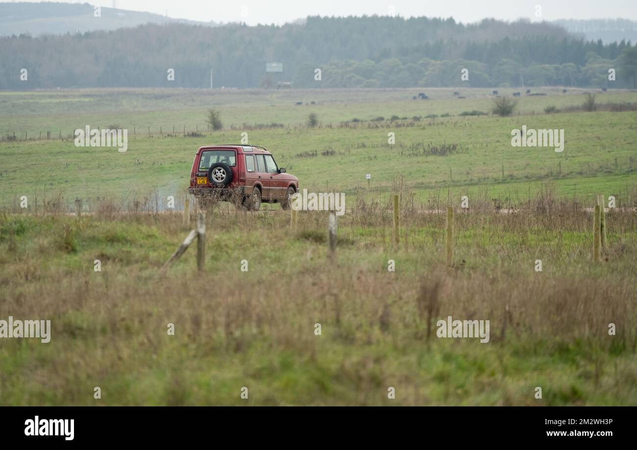 land rover discovery 4x4 off-road vehicle being driven along a mud track in open countryside, Wiltshire UK Stock Photo
