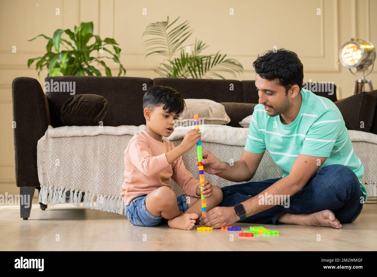 Happy smiling kid and father playing with toys while sitting on floor at home - concept of entertainment, support and family bonding Stock Photo