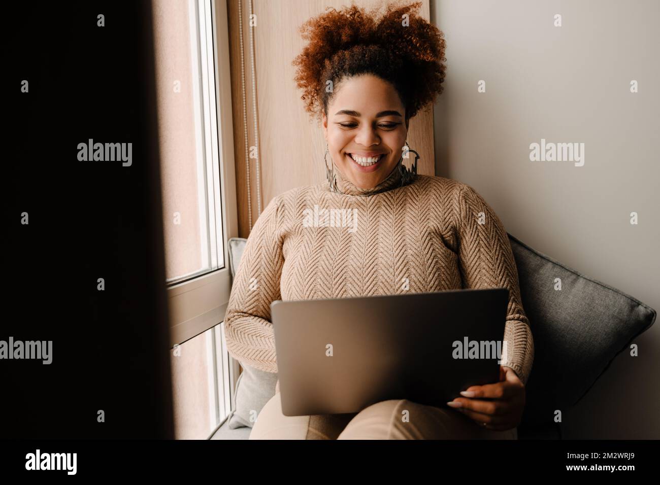 Young beautiful happy smiling african woman with laptop sitting on ...