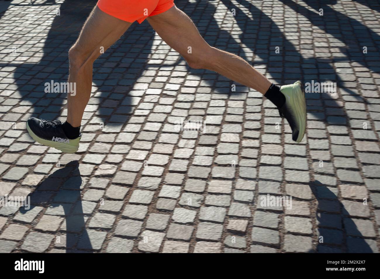Running Race, Male Feet on Porphyry Cobblestone Stock Photo