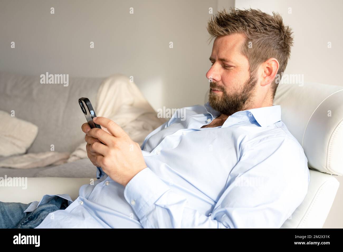 Young handsome man at home using smartphone Stock Photo