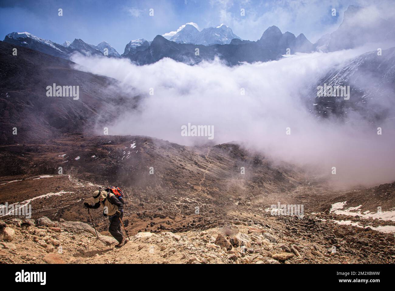 Climbing to Renjo La (pass) at 18,000 feet as clouds cover Gokyo Lake, but allowing distant views of Mount Everest, Nuptse and Lhotse. Stock Photo