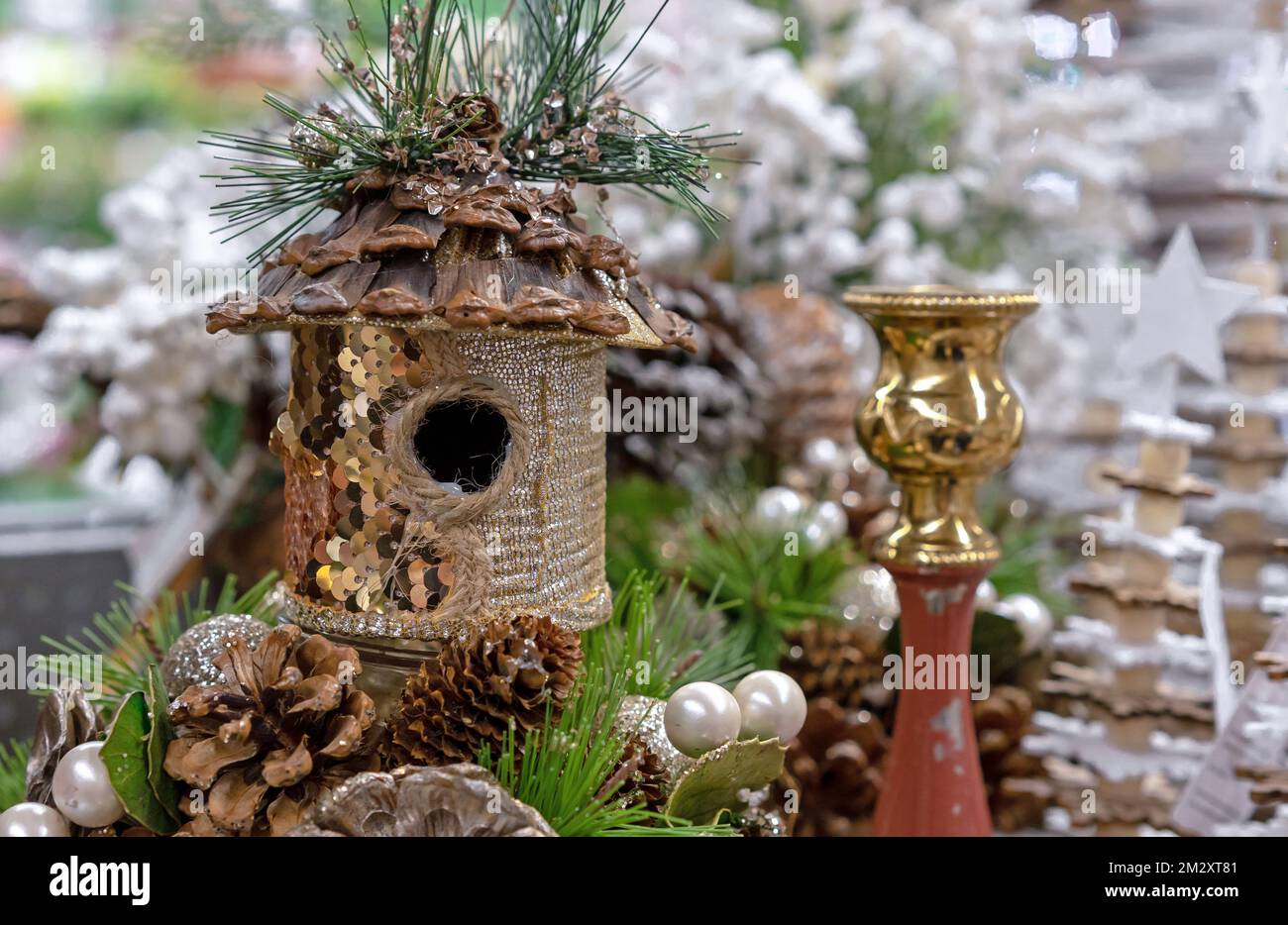 Birdhouse with gold sequins in a Christmas composition with cones and a candlestick. Stock Photo