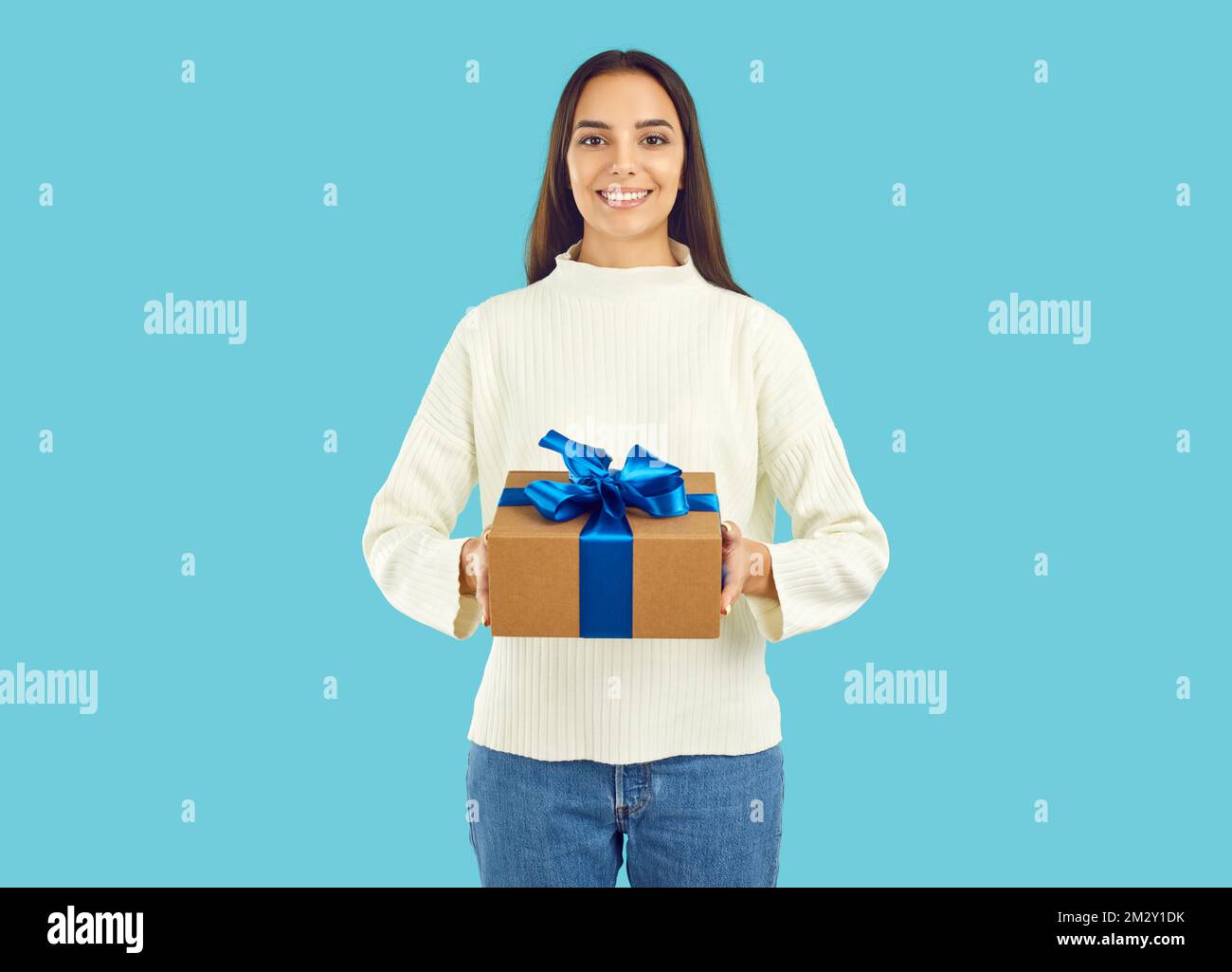 Studio portrait of happy beautiful young woman holding gift box with Christmas present Stock Photo