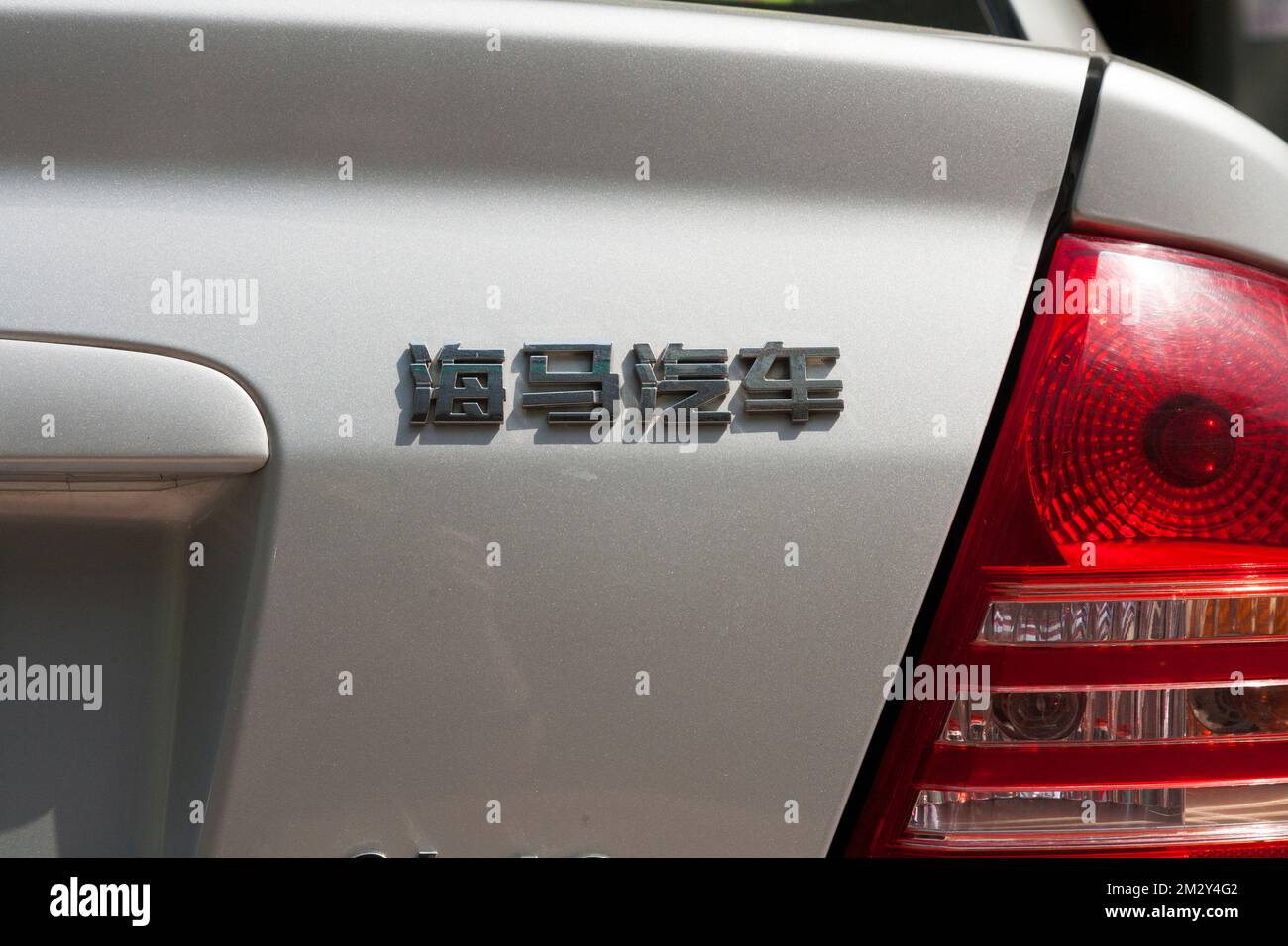 Mazda 323 car rear with section of numberplate and model written in Chinese characters / writing model name of vehicle in China. Xian, China. (125) Stock Photo
