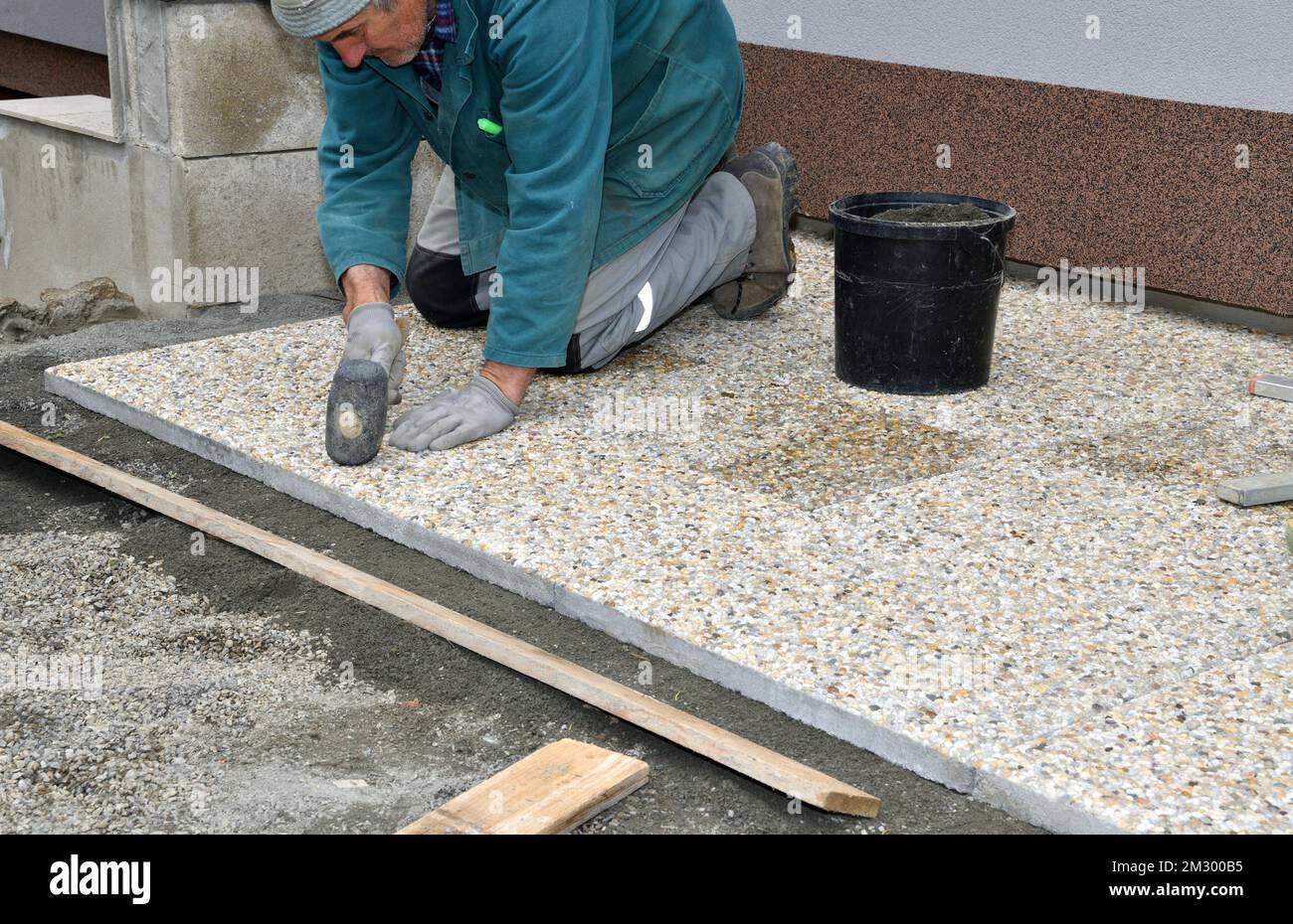Paver on the knee lays concrete paving stone on the sidewalk Stock