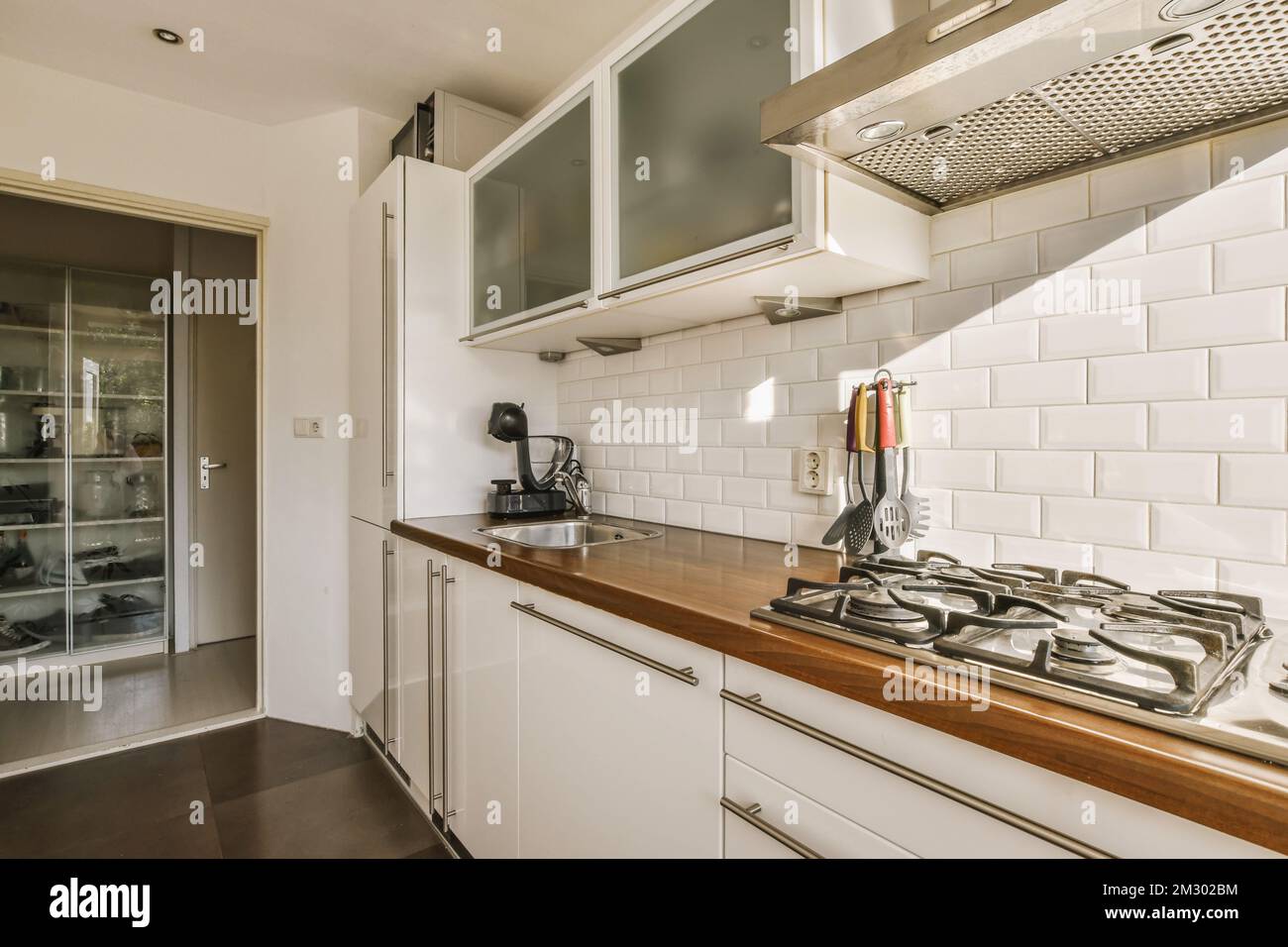 a kitchen with white tiles and wood counter tops on the counters in front of the stove, oven and dishwasher Stock Photo