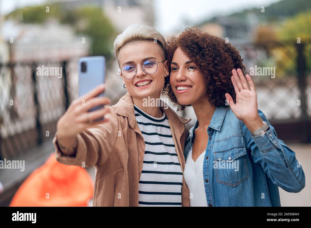 Two attractive joyous ladies taking a selfie on the veranda Stock Photo