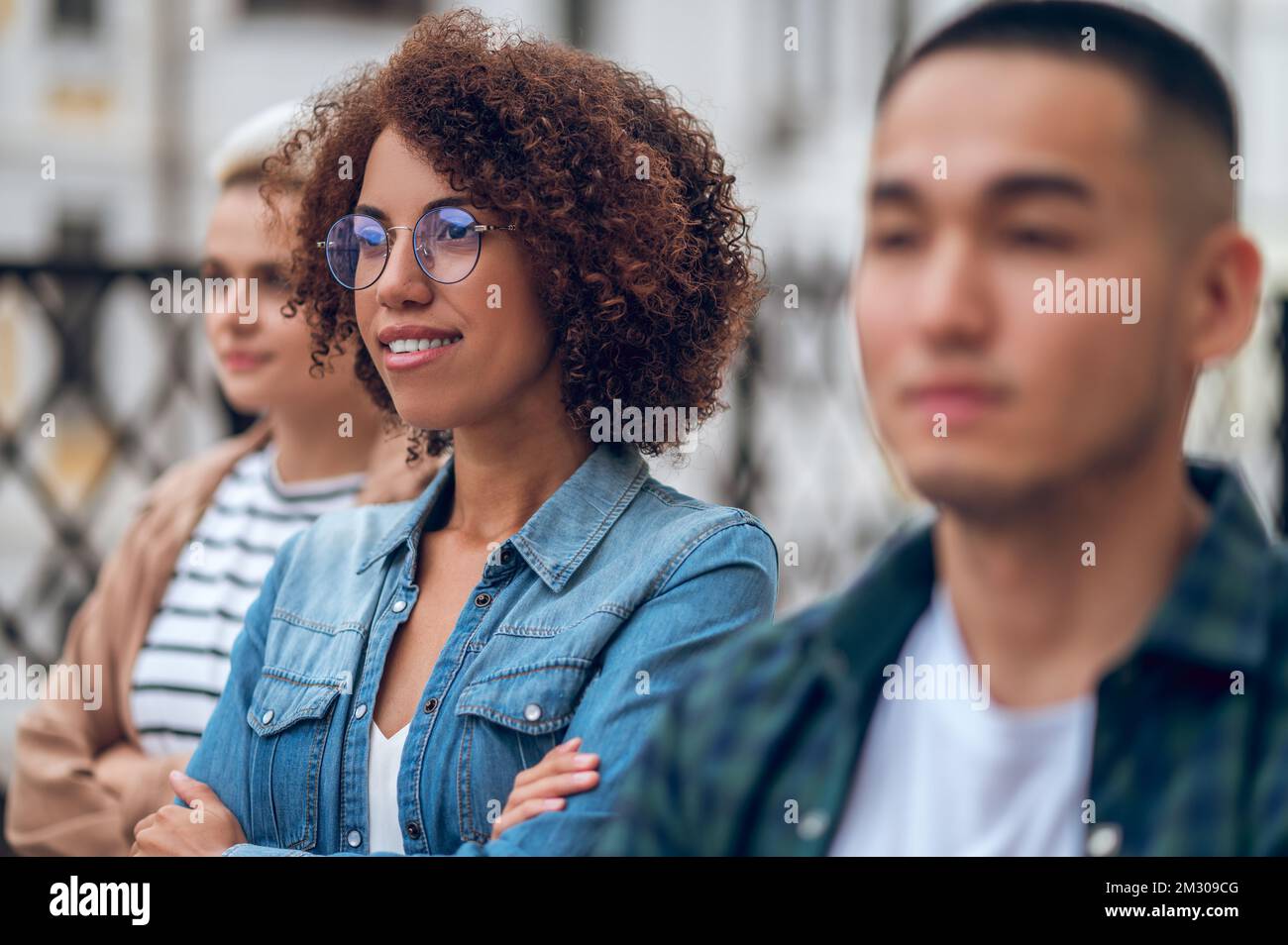 Cheerful good-looking lady and her friends looking into the distance Stock Photo