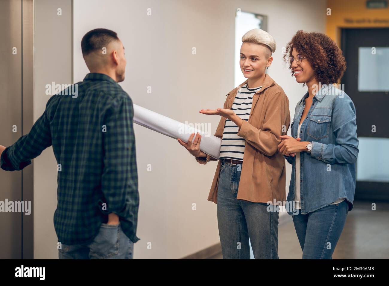 Three company employees waiting together for the elevator Stock Photo