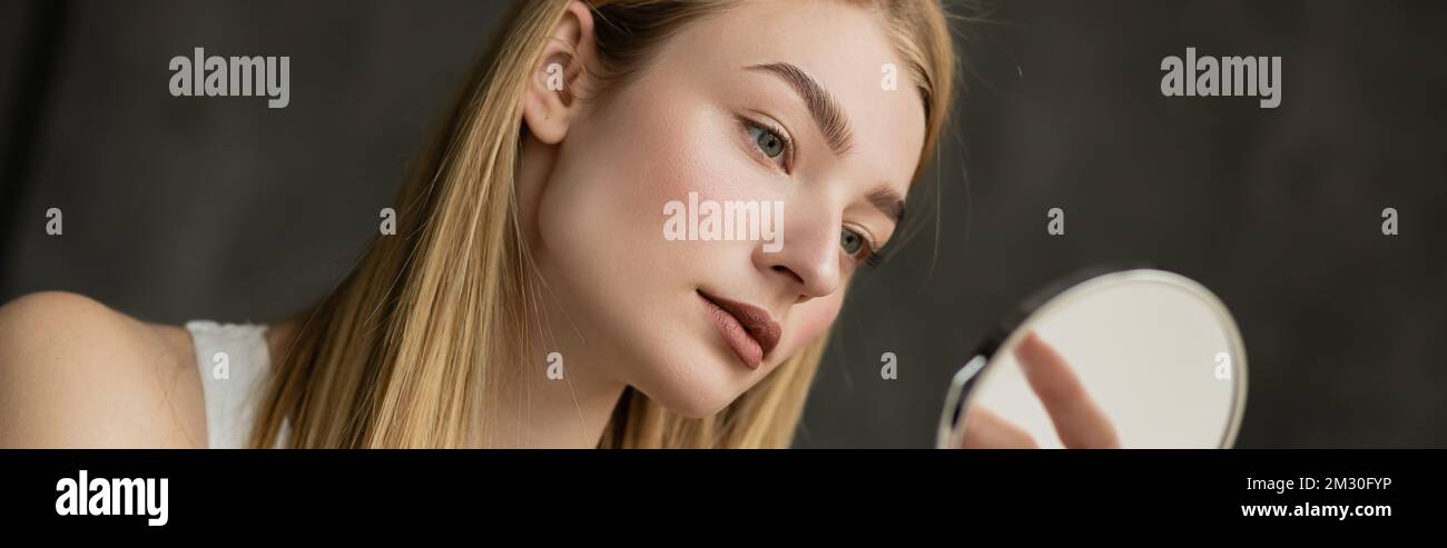 Pretty young woman looking at blurred mirror at home, banner,stock image Stock Photo