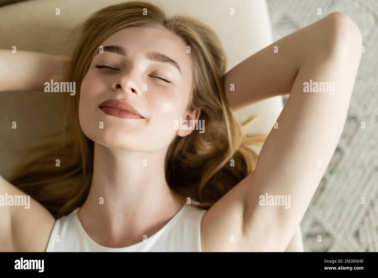 Top view of pleased young woman relaxing on couch at home,stock image